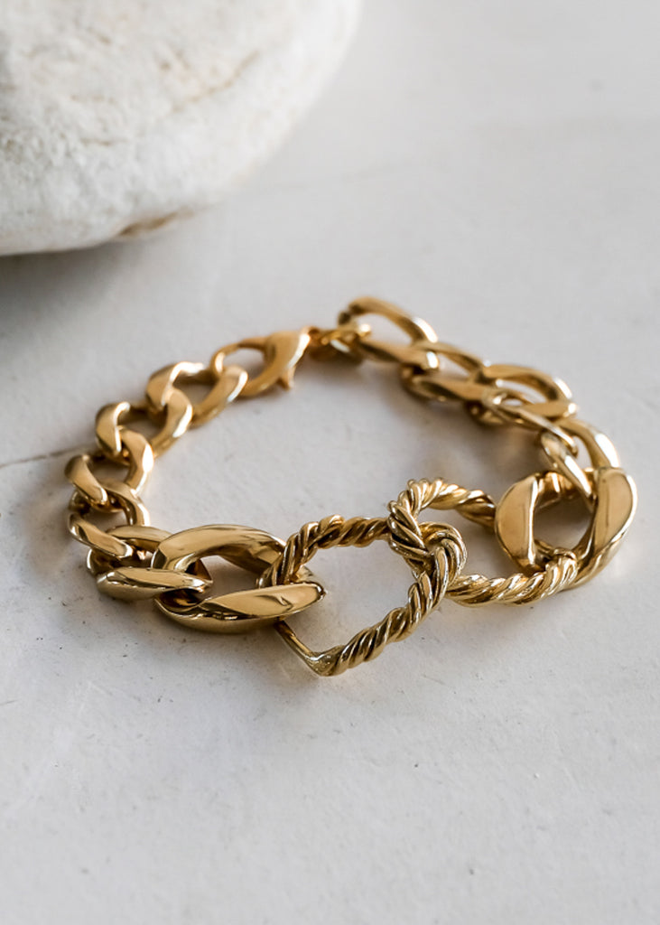 Gold link, chunky chain bracelet, place on a white surface