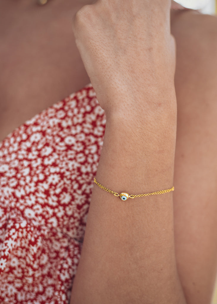 close up of woman's hand, in red dress with mataki bracelet, gold