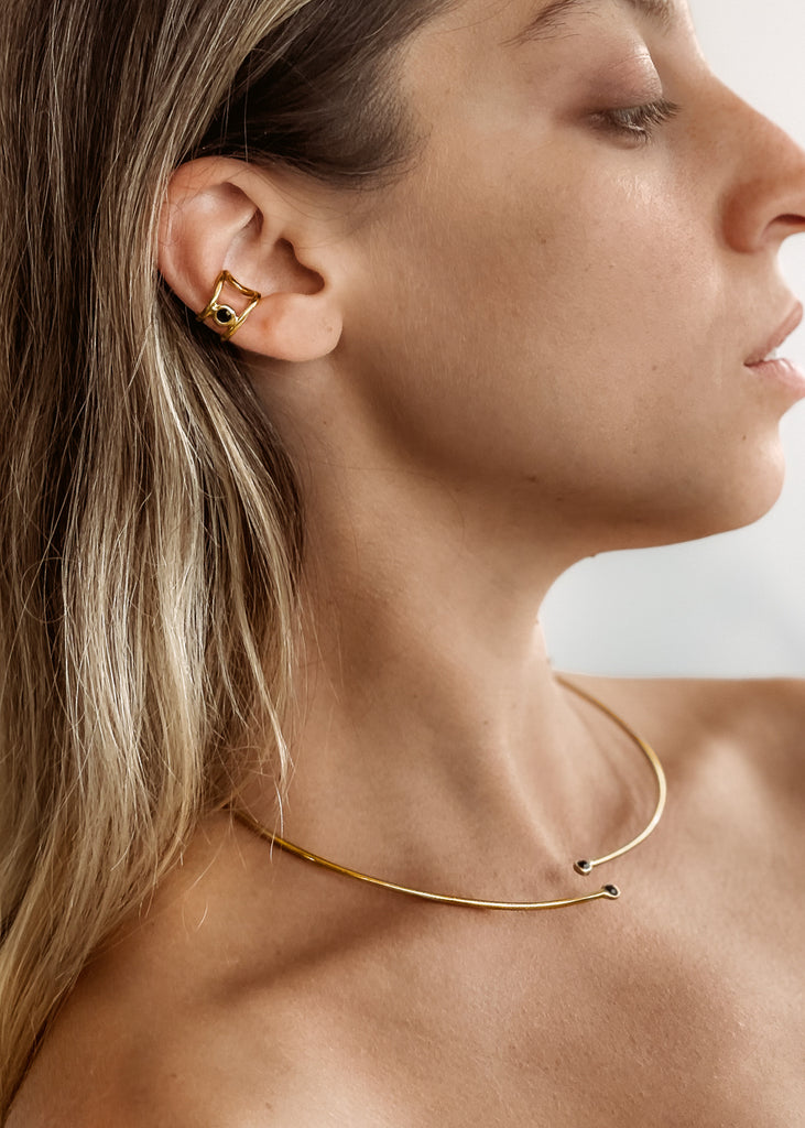 Χειροποίητο ear cuff σκουλαρίκι χρυσό με μία πέτρα Swarovski μαύρη, φορεμένο στο αυτί μοντέλου.