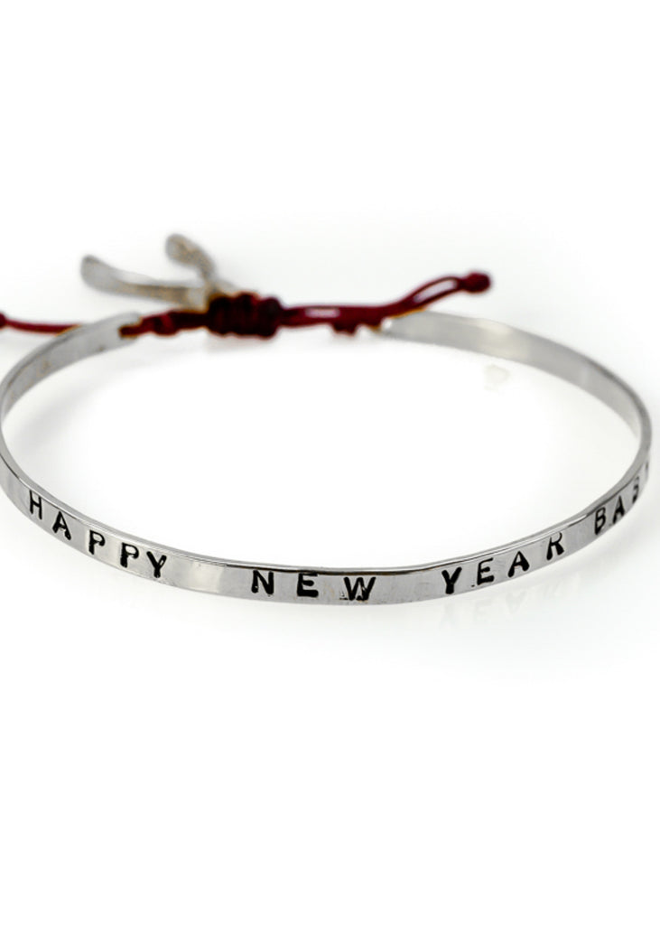 Handmade, gold plated brass, adjustable, red cord tie, charm bracelet, stamped with the phrase Happy New Year Baby