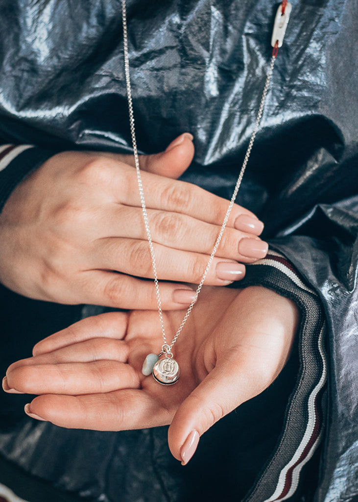 Female's hands, showing off a handmade, platinum plated, Turtle Luck charm necklace