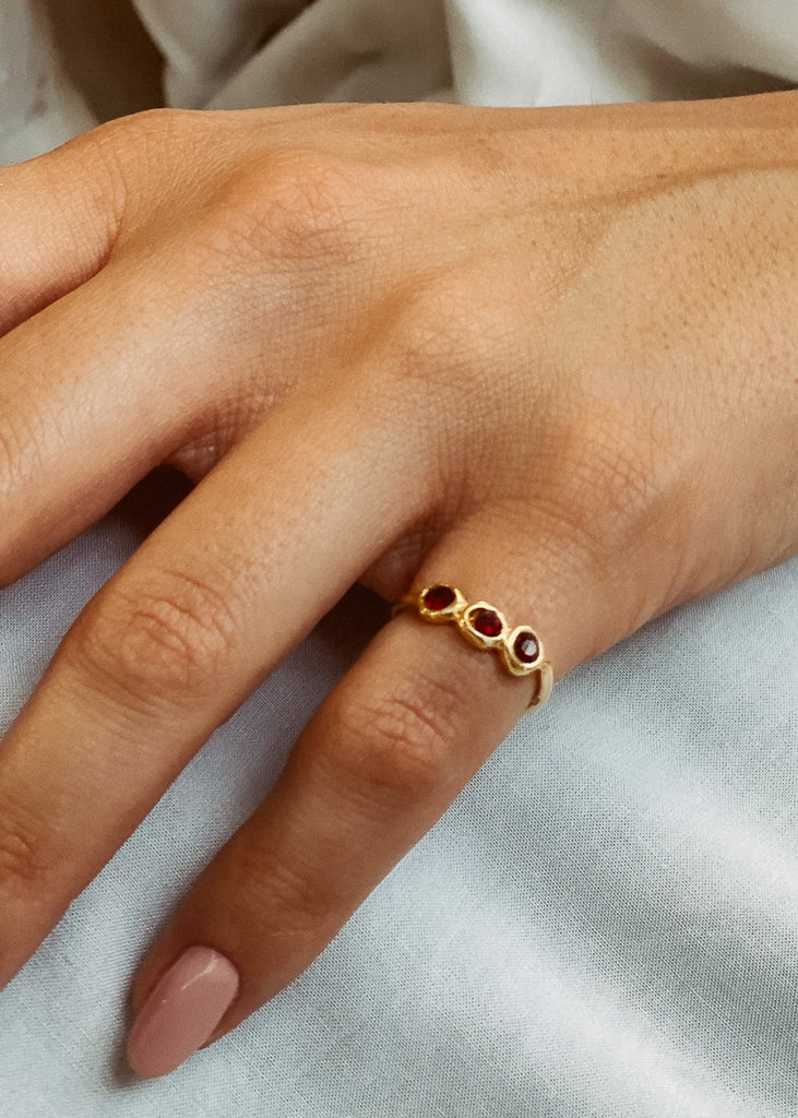 Χειροποίητο δαχτυλίδι Eday χρυσό με τρεις πέτρες Swarovski μπορντώ, φορεμένο στο χέρι μοντέλου.