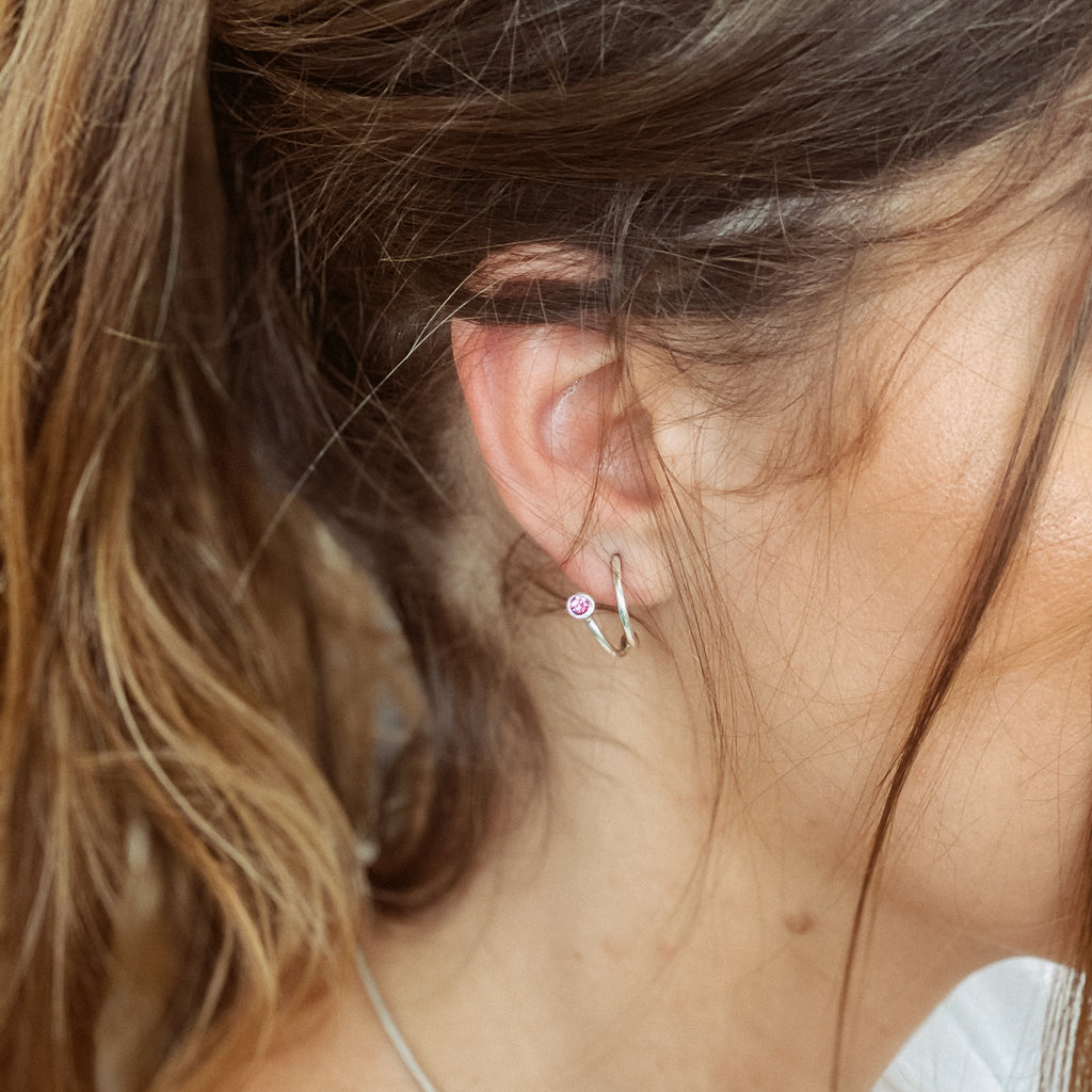Χειροποίητο σκουλαρίκι ασημί με μία πέτρα Swarovski ροζ, φορεμένο στο αυτί μοντέλου.