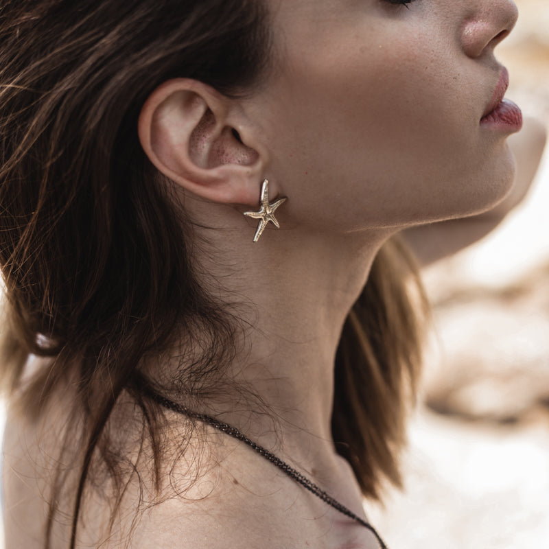 girl on the beach wearing Small Starfish, handmade earrings gold