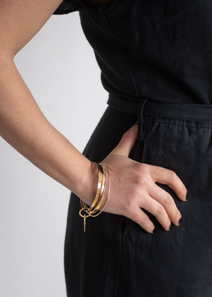 woman in black with  right hand on hip wearing a gold multi bangle bracelet by 3rd Floor Coordinates Line