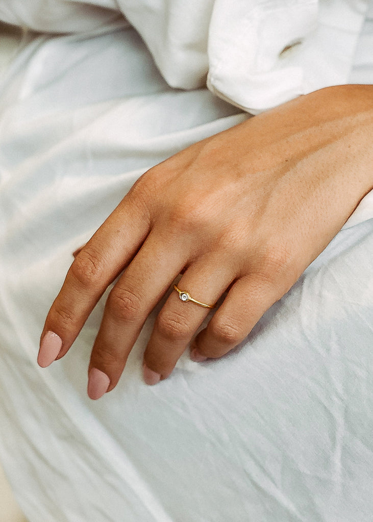 Χειροποίητο δαχτυλίδι Eday χρυσό με μία πέτρα swarovksi διάφανη, φορεμένο στο χέρι μοντέλου.