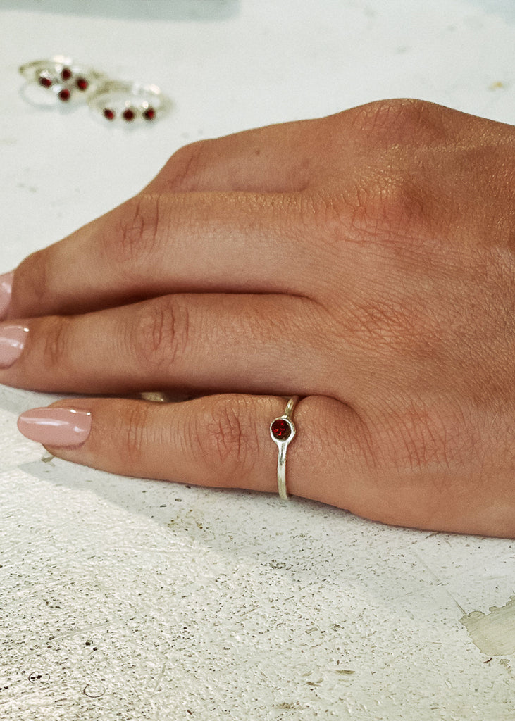 Χειροποίητο δαχτυλίδι Eday ασημί με μία πέτρα swarovksi σκούρο κόκκινο, φορεμένο στο χέρι μοντέλου.