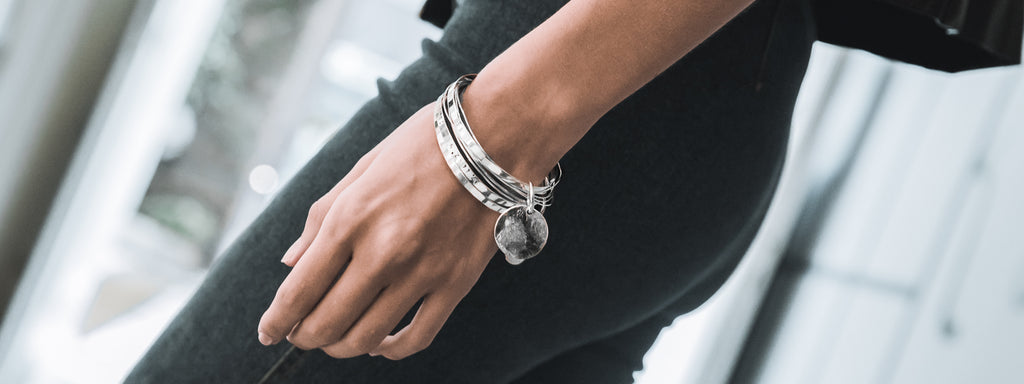 woman in black, wearing taxidi coordinates bracelet, silver