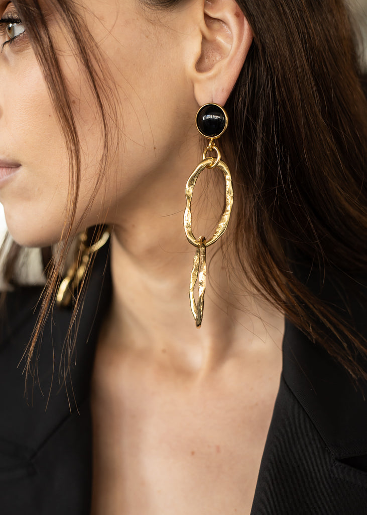 woman, is wearing a double link, gold colored, pendant earring