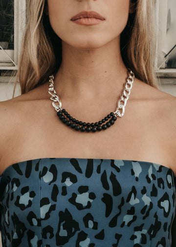 Female in blue camouflage, strapless blouse. On her neck she is wearing a silver chain, and black pearls necklace by 3rd Floor