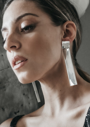Beautiful, female model. Hair pulled back tightly. She is wearing a pair of silver, rectangular, Silhouette, earrings by 3rd Floor Handmade Jewellery