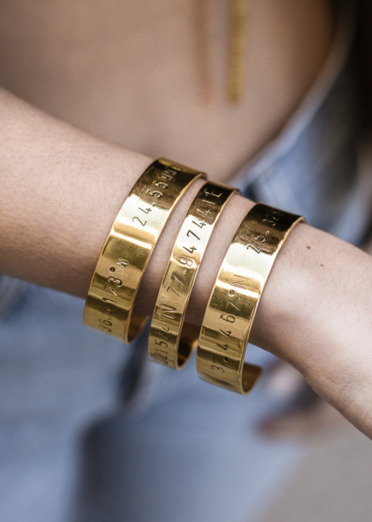 close-up woman, with handmade gold plated adjustable bangle stamped close-up girl,with latitude and longitude coordinates, bracelets