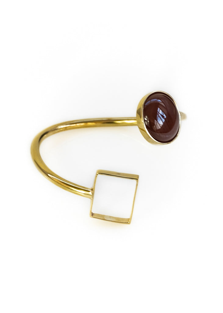 Photo of a gold, spiral shaped bracelet, with a brown stone on one end and a square on the other Χειροποίητο βραχιόλι Felicity χρυσό με καφέ πέτρα