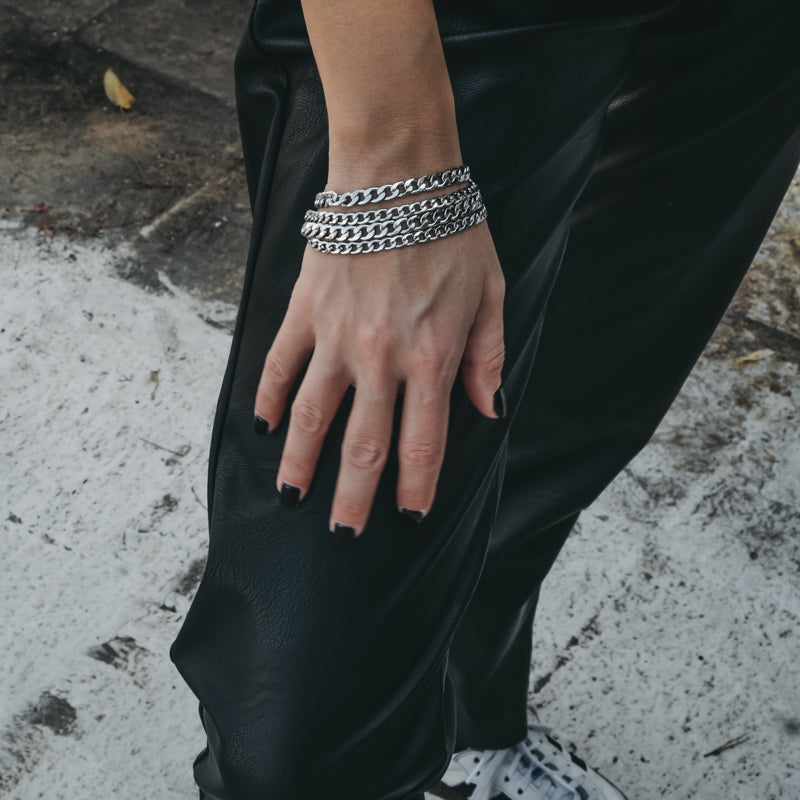 Female's, right hand rested on her right thigh. On her wrist, a silver, four chain bracelet