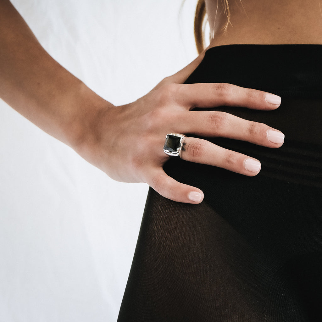 Χέρι κοπέλας που φοράει το χειροποίητο δαχτυλίδι Zelva ασημί με τετράγωνη μαύρη πέτρα 