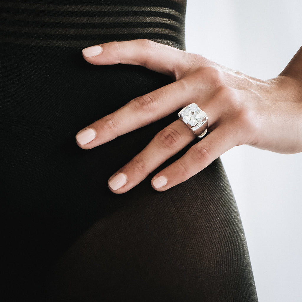 Χέρι κοπέλας που φοράει το χειροποίητο δαχτυλίδι Zelva ασημί με τετράγωνη διάφανη πέτρα
