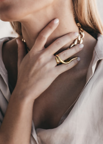 Female's right hand, hearing an Avalon, gold ring, on her wedding ring finger