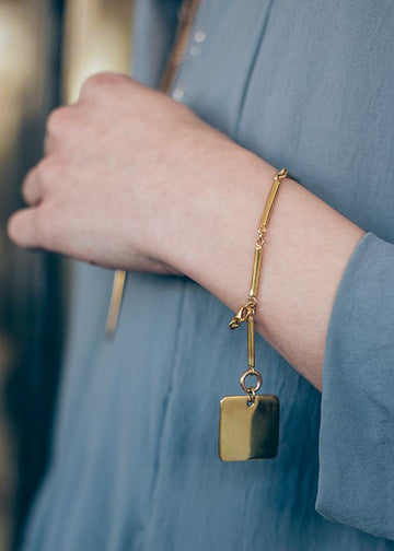 Close up of girl's hand wearing silver handmade bracelet audacity, gold.