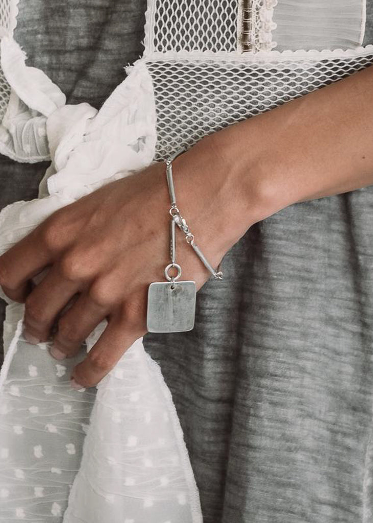 Close up of girl's hand wearing silver handmade bracelet audacity.