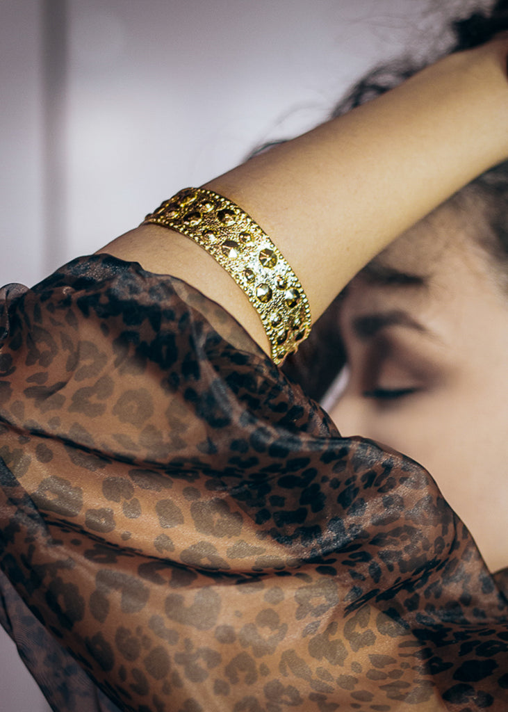 Photo of brunette girl in profile. On her left forearm she is wearing a gold bracelet, by 3rd Floor Handmade Jewellery