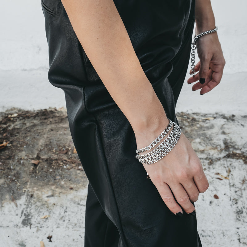 Cropped photo of female in black leather pants. On her wrist, she is wearing a four chain bracelet