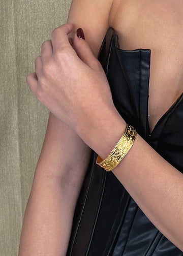 Cropped photo of female. On her left arm, she is wearing a gold bangle adele bracelet, by 3rd Floor