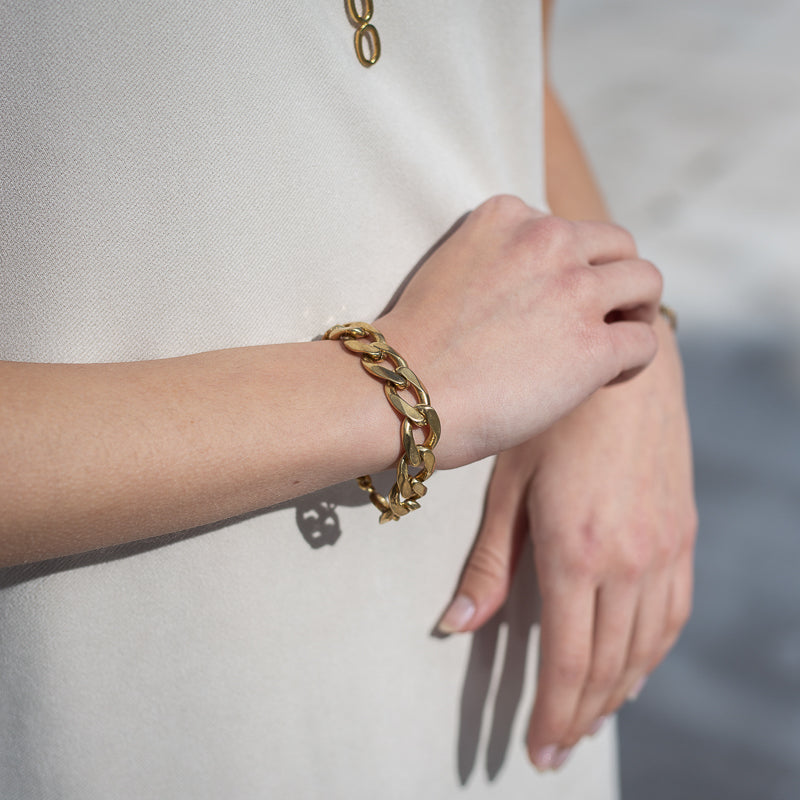 Close up of female's hands. On her left wrist she is wearing a Bilboe, handmade, gold plated brass, bracelet. 