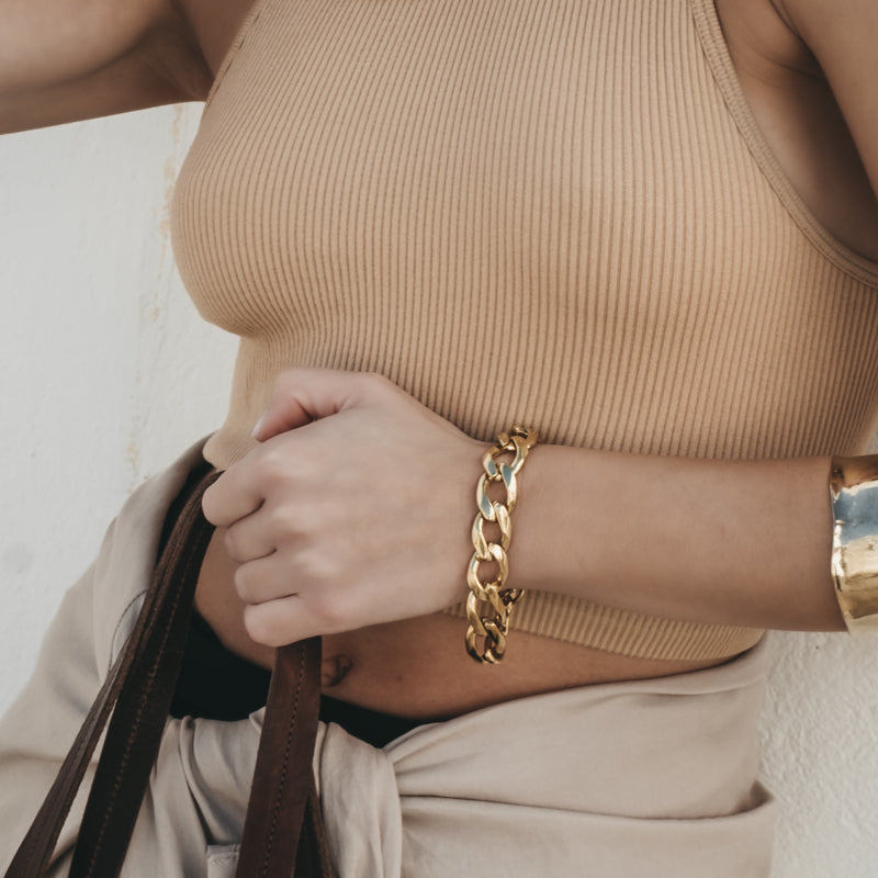 Close up of female's hands. On her left wrist she is wearing a Bilboe, handmade, gold  brass, bracelet.