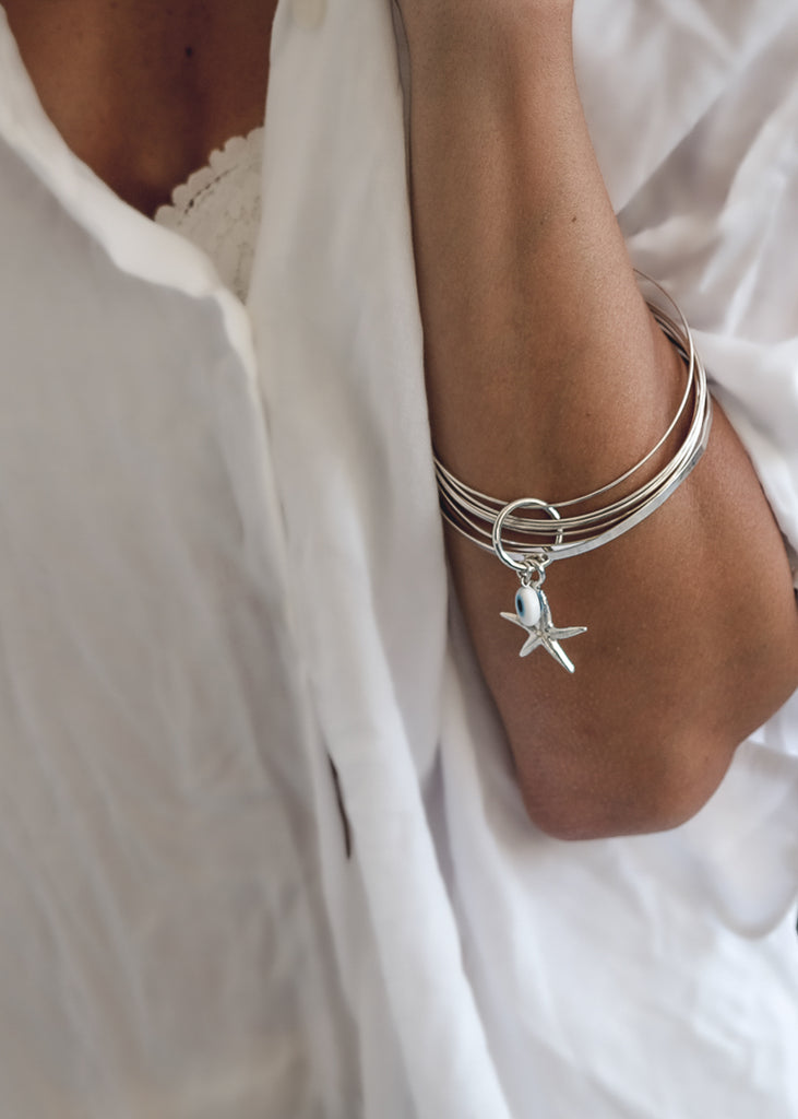woman, in white shirt-wearing a Thallo Star. Handmade, silver plated brass bracelet