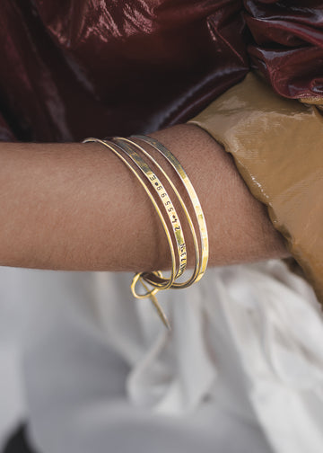 woman wearing,in the right hand,  a gold bangle bracelet by 3rd Floor Coordinates Line