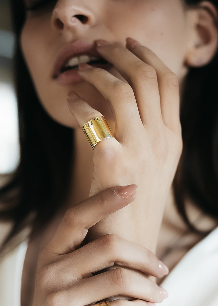 Close up of girl's hands. She is wearing handmade, gold, coordinates ring.