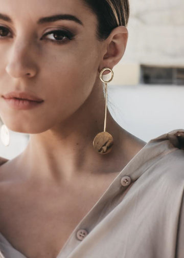 Beautiful female, looking straight into the camer. She is wearing gold, pendant earrings by 3rd Floor handmade jewellery