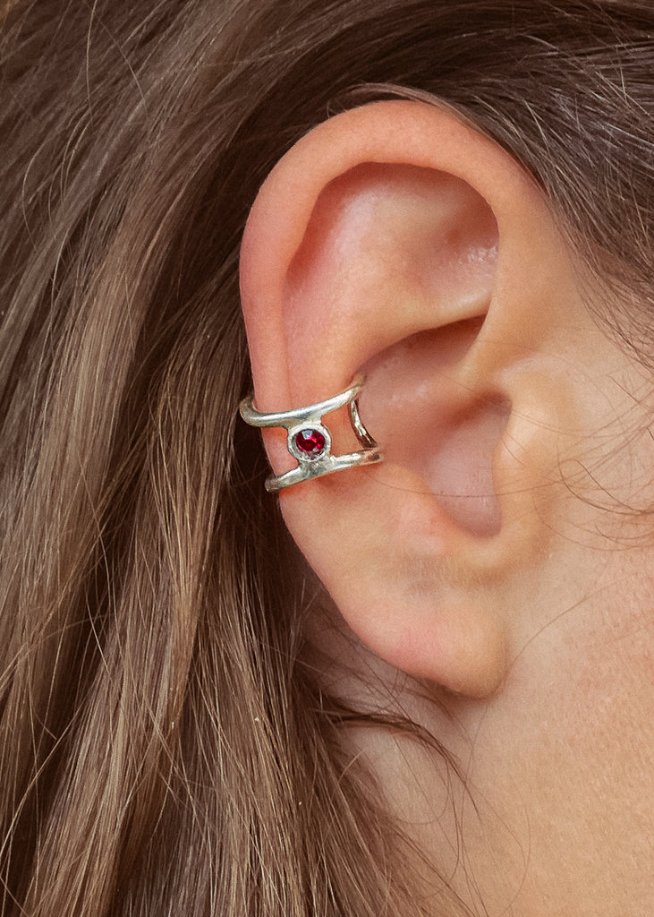Χειροποίητο ear cuff σκουλαρίκι ασημί με μία πέτρα Swarovski κόκκινη, φορεμένο στο αυτί μοντέλου.