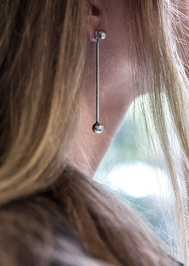 close up to a blonde woman wearing the pendulum earring in silver color