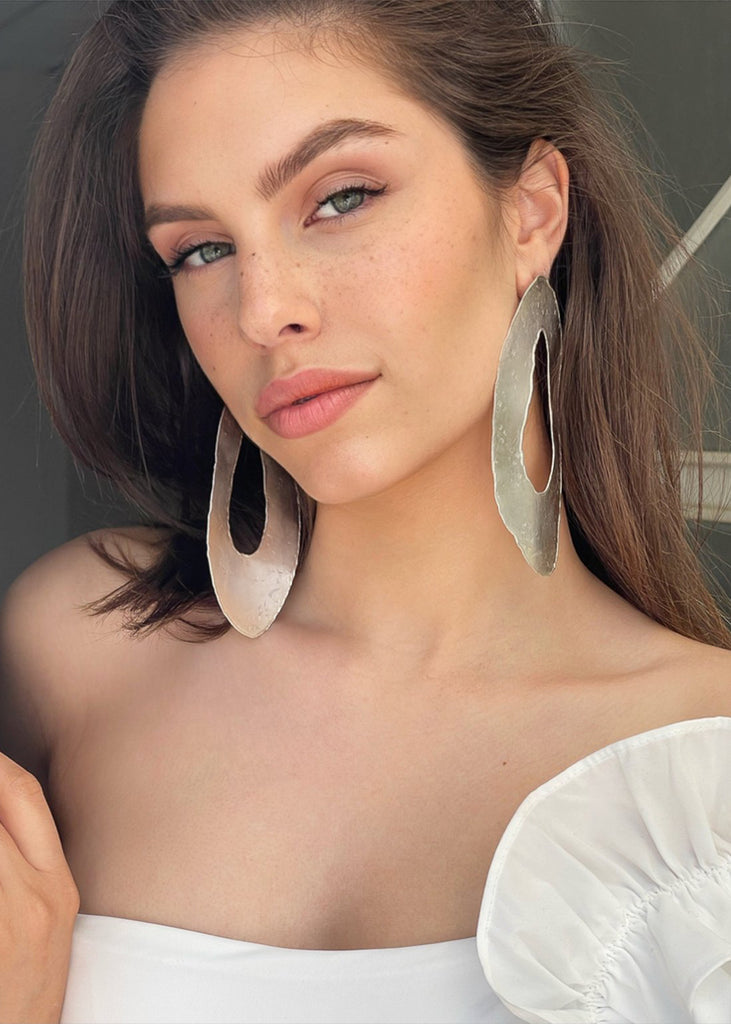 young model wearing the Toma earrings in silver color