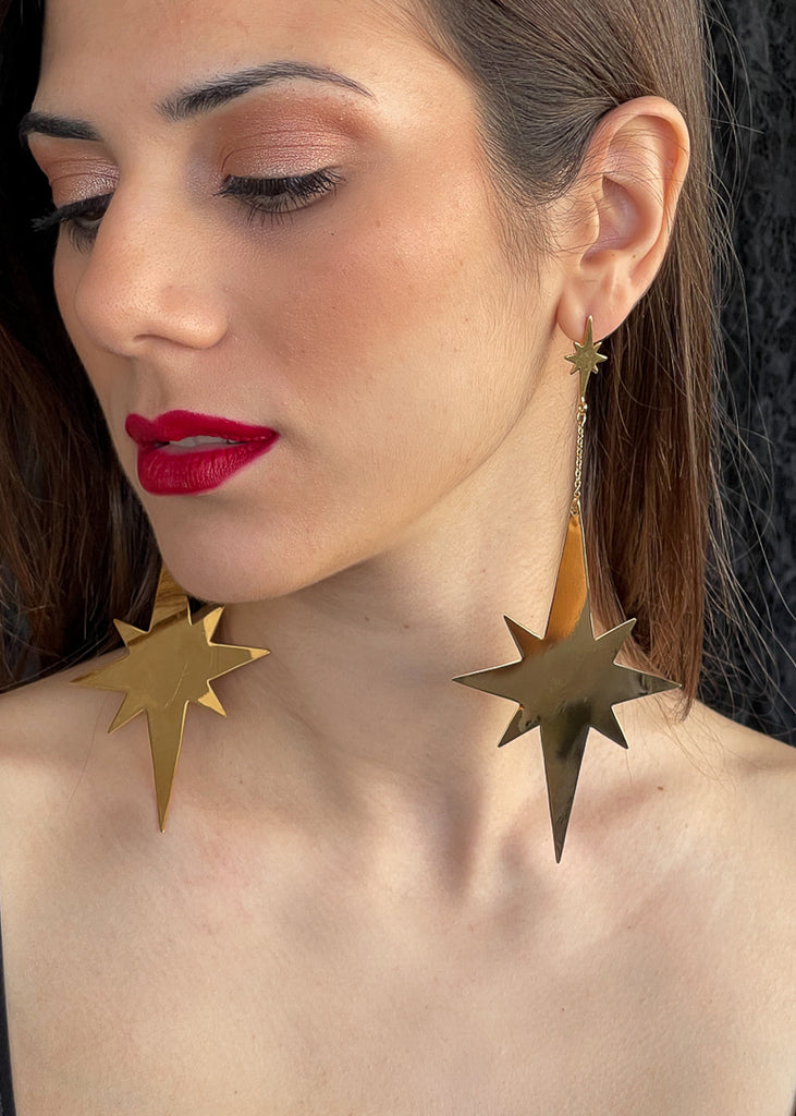 close portrait of a woman with red lipstick wearing the Twinkler handmade earrings in gold color