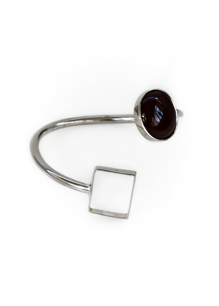 Silver, spiral shaped bracelet, with a black stone on one end and a square on the other