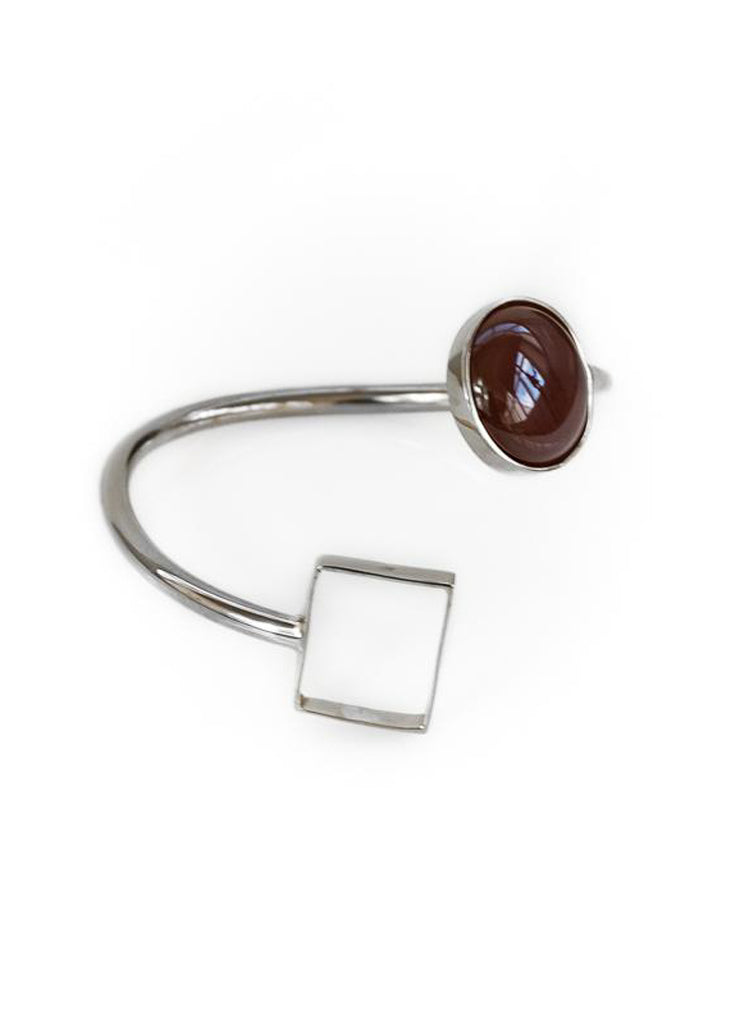Silver, spiral shaped bracelet, with a brown stone on one end and a square on the other