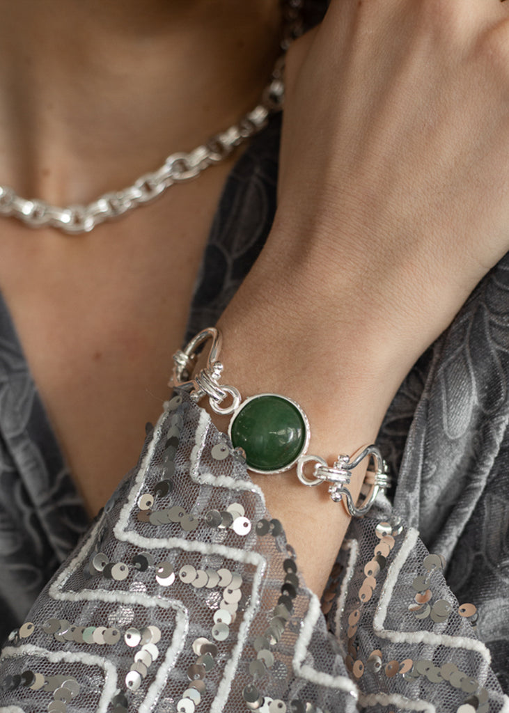 Γυναίκα φοράει στο χέρι ασημί βραχιόλι Stone Temptress με πράσινη πέτρα .