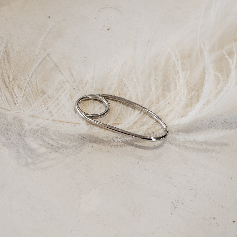 Dharma. silver, statement ring placed on a white feather