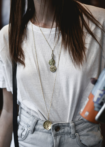 Girl in white blouse wearing 3rd Floor Handmade silver chain necklace with two charms portraying Hercules taming snakes