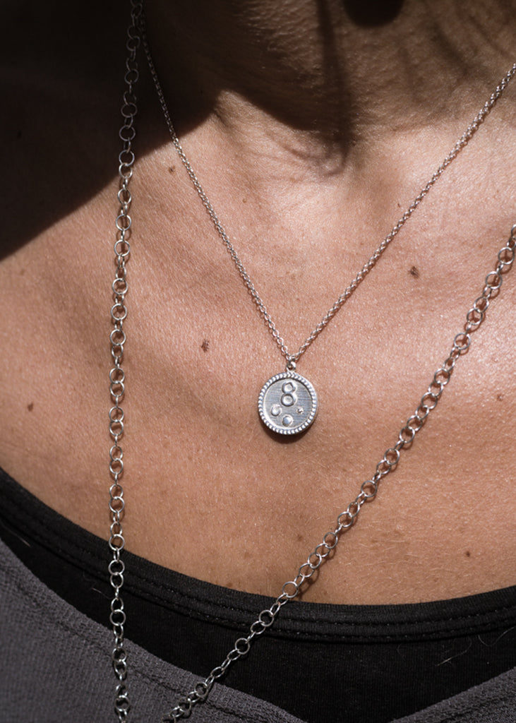 Extreme close up of woman's chest. She is wearing a Tupac, silver, handmade necklace, made in Athens by 3rd Floor Workshop
