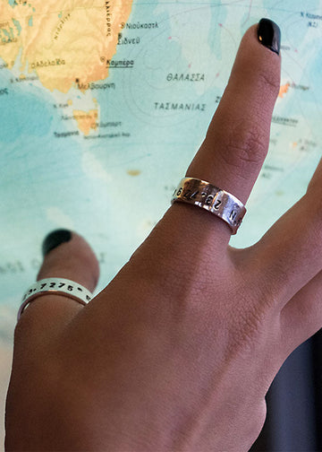 Close up of girl's hand touching a globe wearing silver Metis adjustable rings on her index and thumb fingers