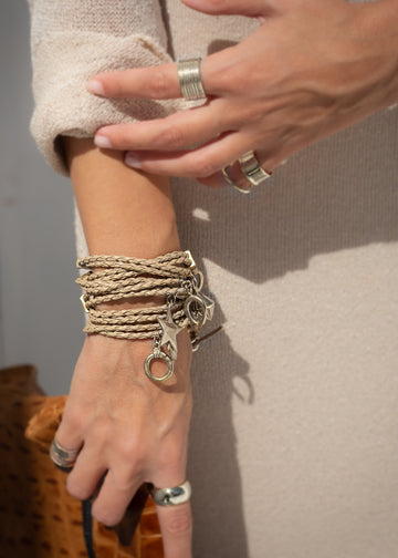 woman's arm with Orbit. Handmade, beige leather, and silver plated brass, charms bracelet. 