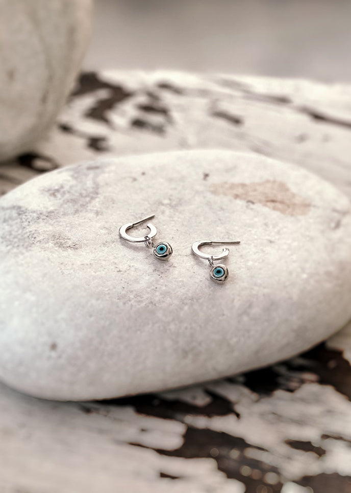 Pair of silver loop earring, with a hanging evil eye