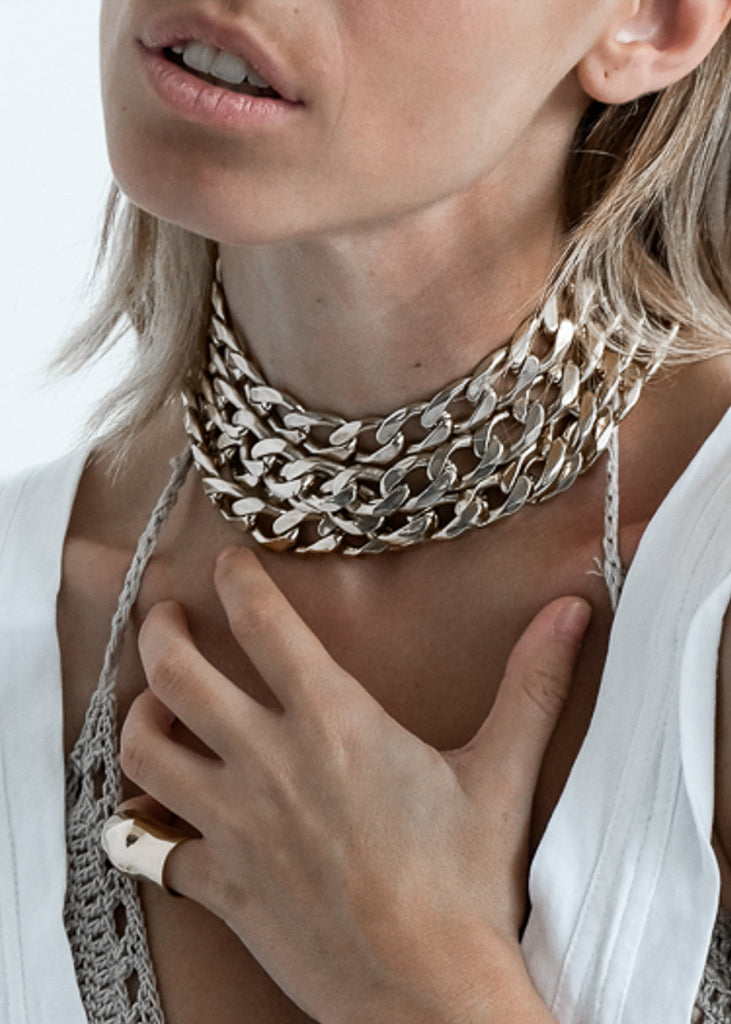 Blond woman in white blouse. She is wearing a Tetra, handmade, silver plated choker, and Punch, silver ring. Jewellery made in Athens Greece, by 3rd Floor Workshop