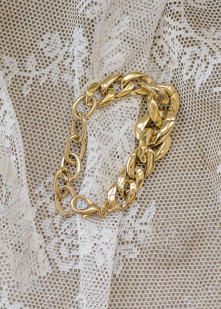 Gold chunky chain bracelet placed on white lace fabric
