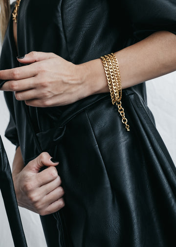 Female in black leather dress. On her left wrist she is wearing a gold, triple chain, Monsoon bracelet by 3rd Floor Handmade Jewellery