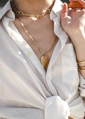 woman in white shirt,wearing silver handmade necklace audacity, gold
