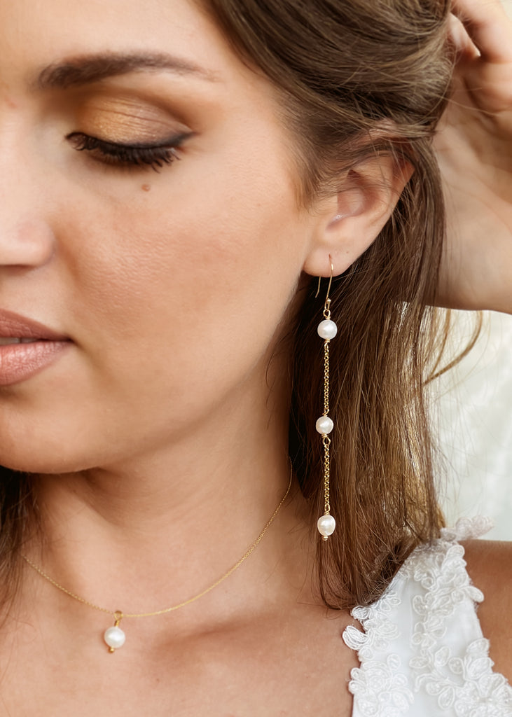 close-up of a bride who is wearing on her left ear the ong dangling earring Timeless with a thin gold plated sterling silver chain and three round white pearls